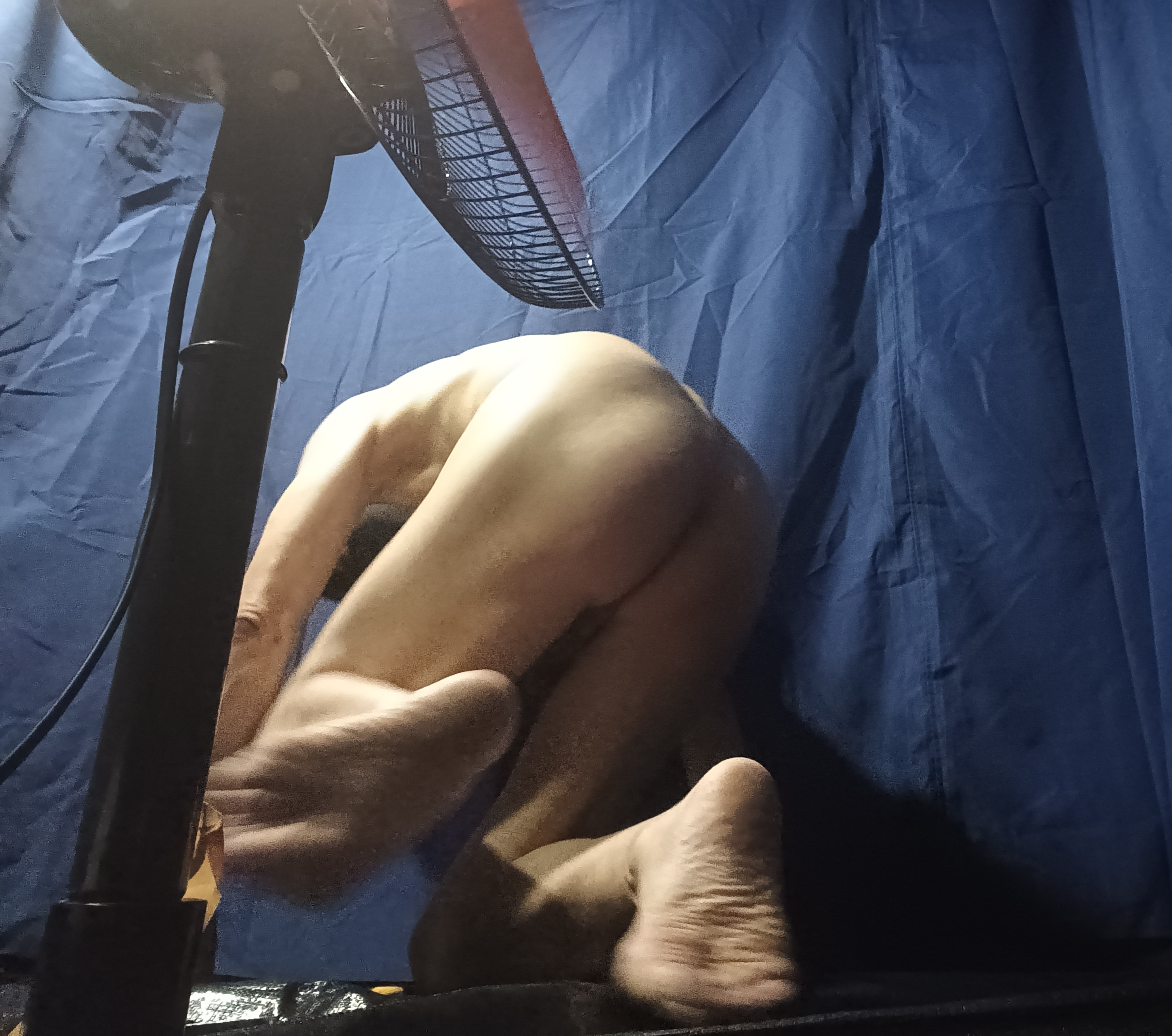 A man being whipped on the butt by a large fan.