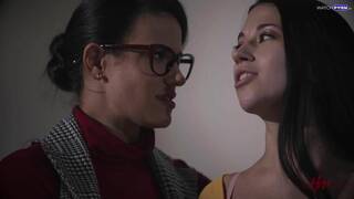 Penny Barber and Alex Coal on a grey sofa and a grey chair in several lesbian scenes